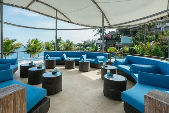 Modern circular lounge area with blue sofas and ocean views at Oneeighty, a premier Bali day club.