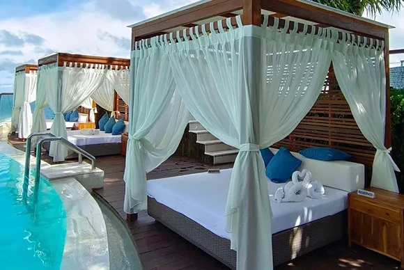 Luxury poolside cabanas with white drapes and blue cushions at Oneeighty day club, Bali.